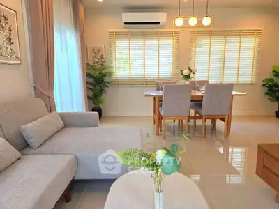 Elegant living room with modern decor and dining area, featuring natural light and stylish furnishings.