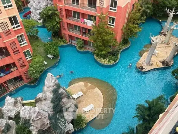 Stunning aerial view of luxury apartment complex with unique pool design and lush greenery.