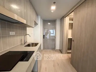 Modern kitchen with sleek cabinetry and electric cooktop in a contemporary apartment.