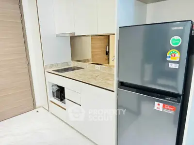 Modern kitchen with sleek cabinetry and stainless steel fridge in a compact layout.