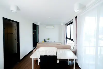 Modern living room with dining area and large windows in a bright apartment.