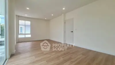 Spacious empty room with wooden flooring and large windows in modern home.