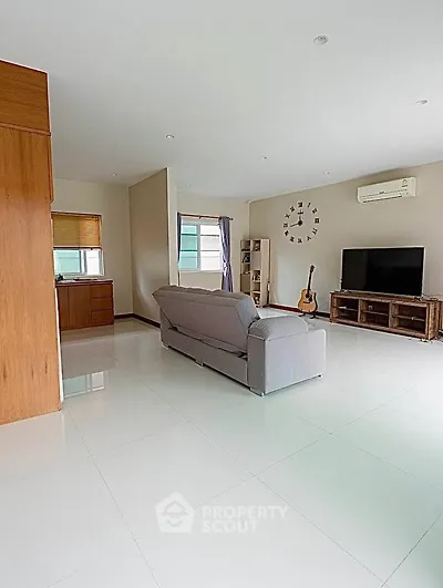 Spacious living room with modern decor and natural light, featuring a cozy sofa and entertainment center.