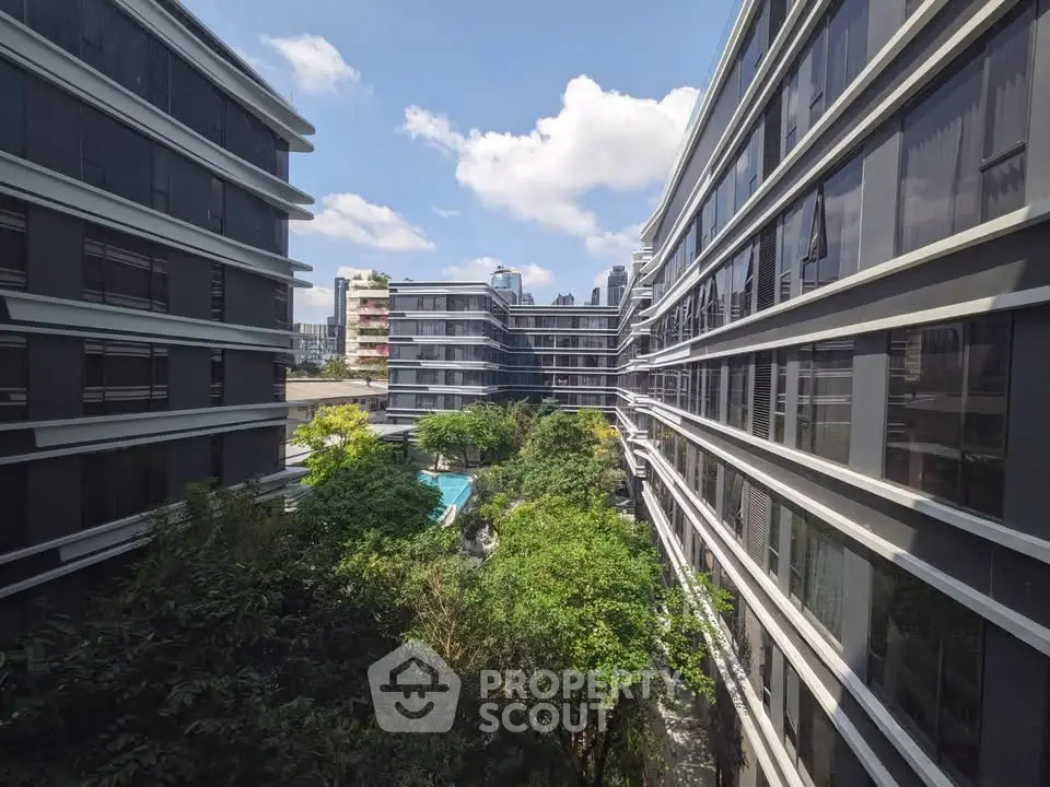 Modern urban apartment complex with lush greenery and city skyline view.