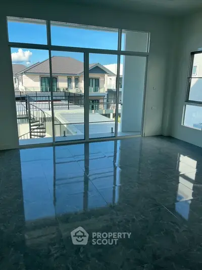 Spacious modern living room with large windows and stunning view of neighboring houses.