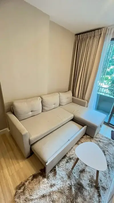 Cozy living room with beige sofa and stylish rug near window with curtains