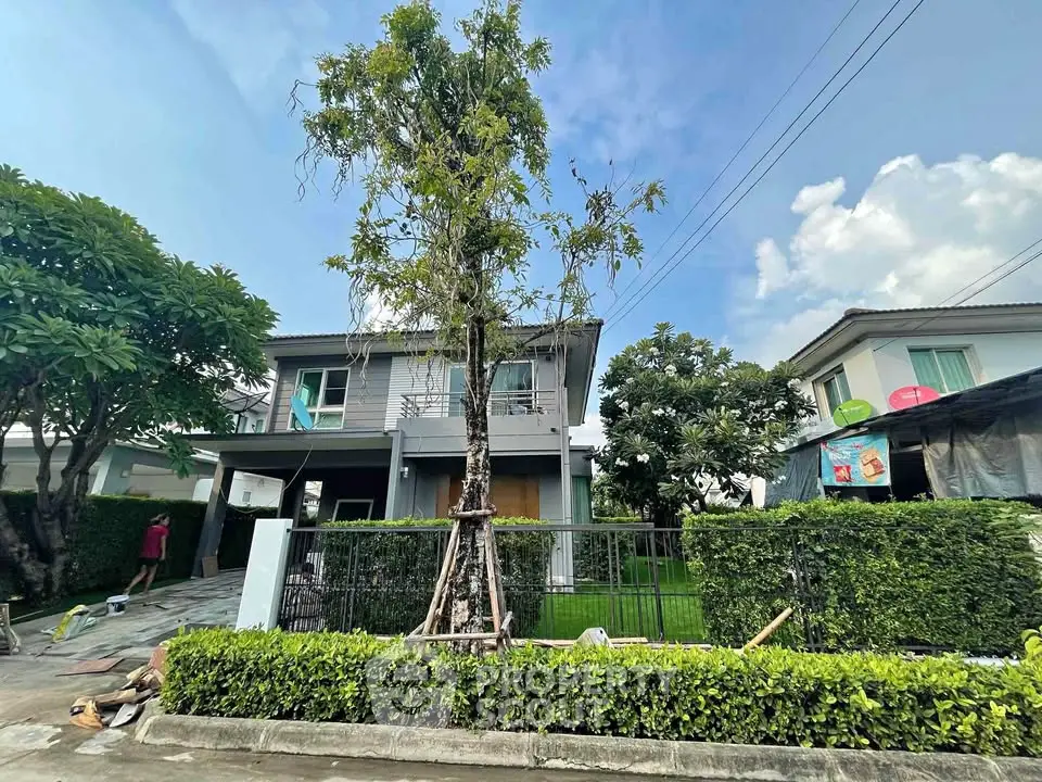 Charming two-story house with lush garden and modern facade in serene neighborhood.