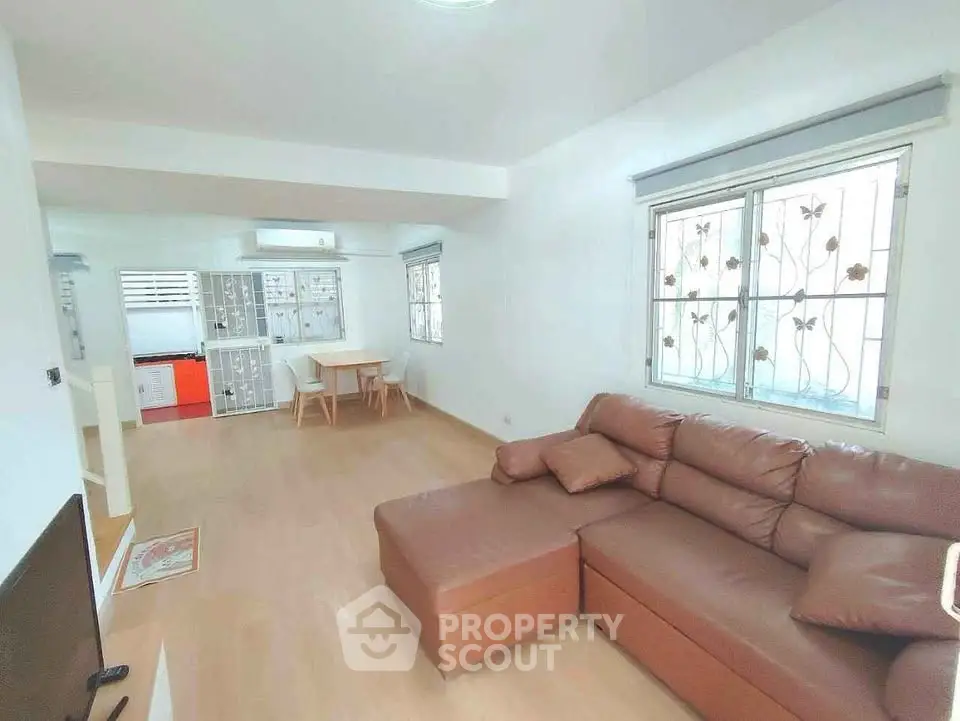 Spacious living room with cozy brown sofa and dining area, perfect for family gatherings.