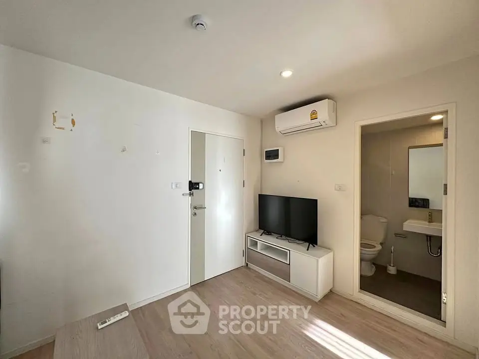 Modern apartment interior with living room and bathroom, featuring sleek design and natural lighting.