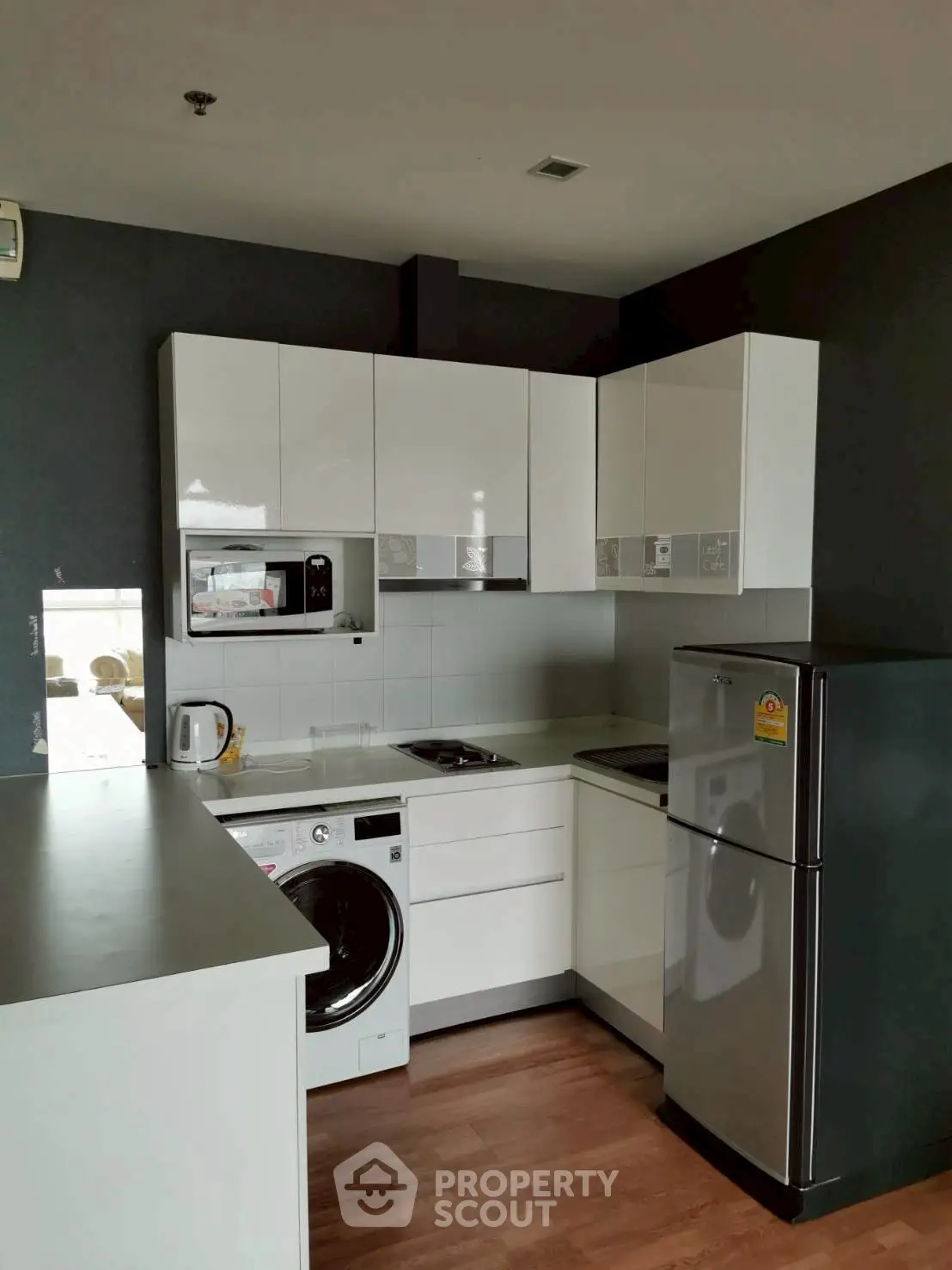 Modern kitchen with sleek white cabinets, washing machine, and stainless steel fridge.