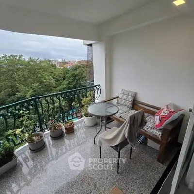 Charming balcony with lush green view and cozy seating area
