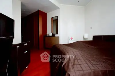 Cozy bedroom with modern furniture and warm wooden flooring, ideal for relaxation.