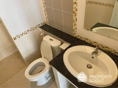 Compact and clean bathroom with white fixtures, mirror, and neutral tile work, ideal for modern living.