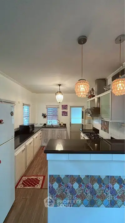 Charming kitchen with modern appliances and stylish lighting in a cozy home.