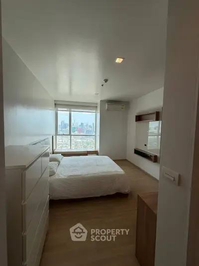 Modern bedroom with city view, featuring minimalist design and large window for natural light.