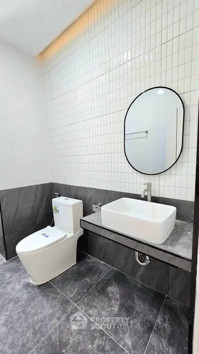 Modern bathroom with sleek design, featuring a stylish sink and toilet against elegant tiled walls.