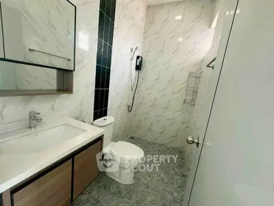 Modern bathroom with sleek design and marble walls, featuring a spacious shower area and elegant fixtures.