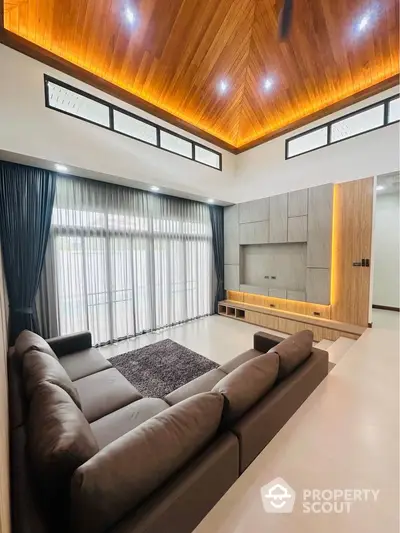 Luxurious living room with high ceiling and modern design, featuring a spacious sofa and elegant lighting.