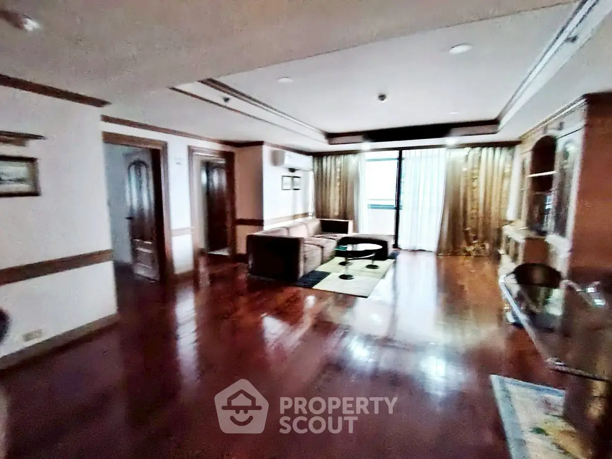 Spacious living room with polished wooden floors and elegant curtains