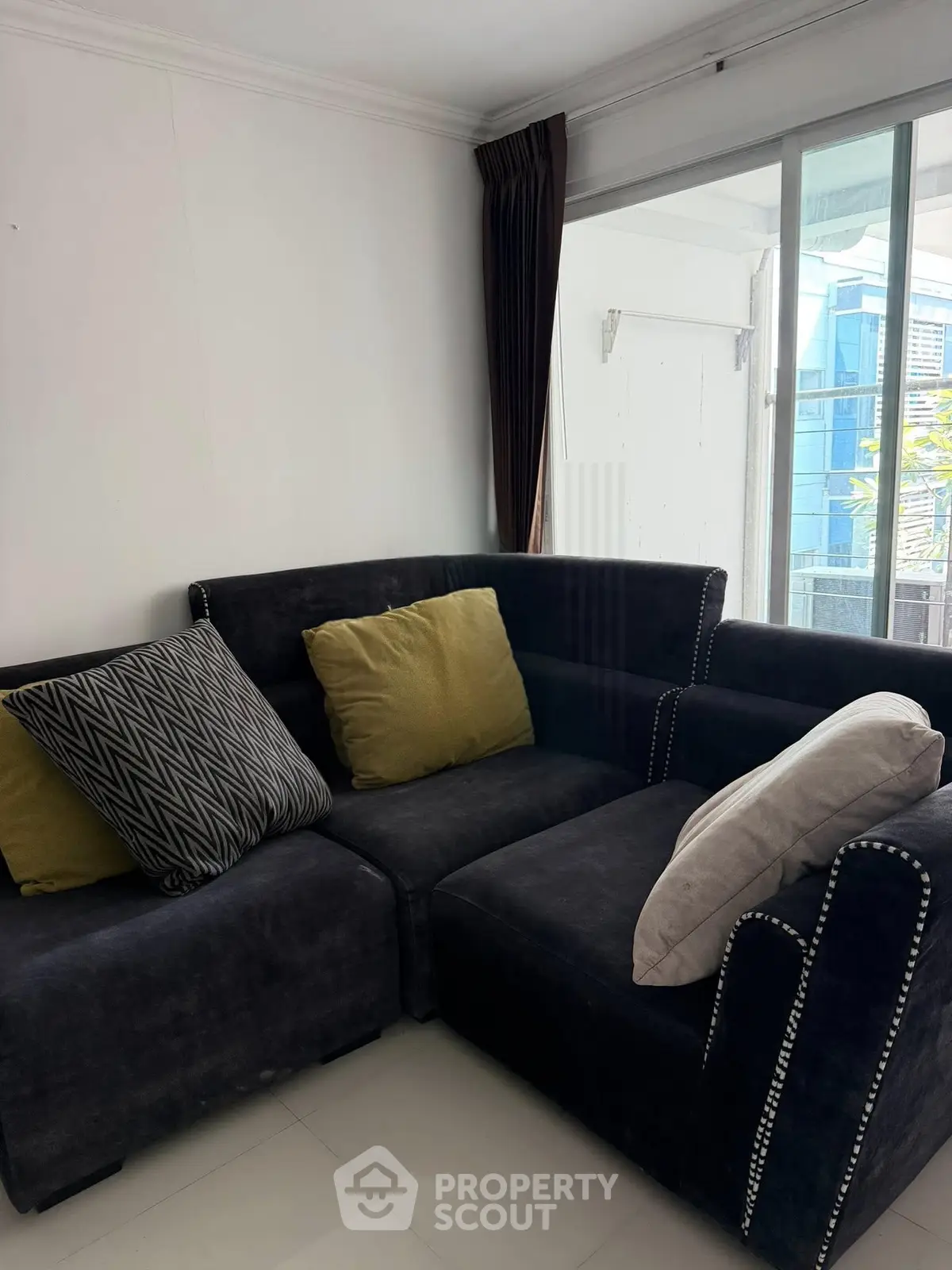 Cozy living room with stylish dark sofa and large windows for natural light.