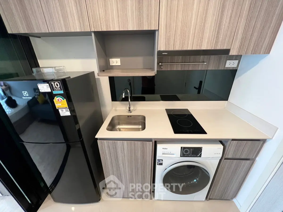 Modern compact kitchen with sleek appliances and stylish cabinetry in a contemporary apartment.