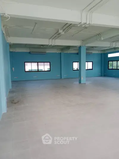 Spacious open-plan commercial space with blue walls and large windows