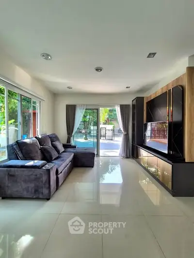 Spacious living room with modern decor and large windows overlooking greenery.