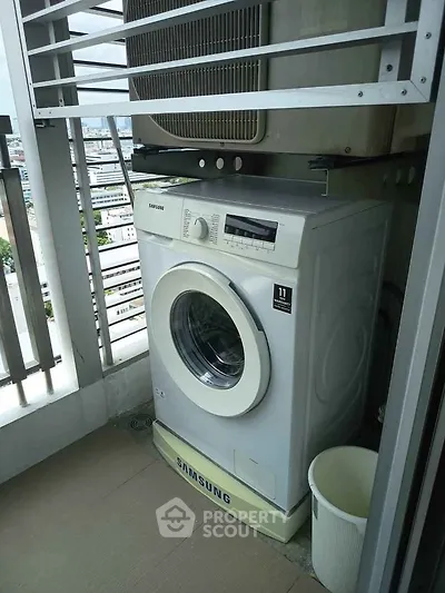 Compact balcony with washing machine and city view, ideal for urban living convenience.