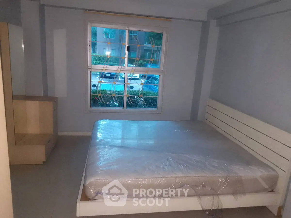 Spacious bedroom with large window and modern bed frame, perfect for comfort and relaxation.