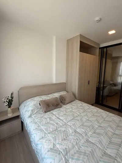 Cozy bedroom with modern decor and ample natural light, featuring a stylish wardrobe and comfortable bedding.