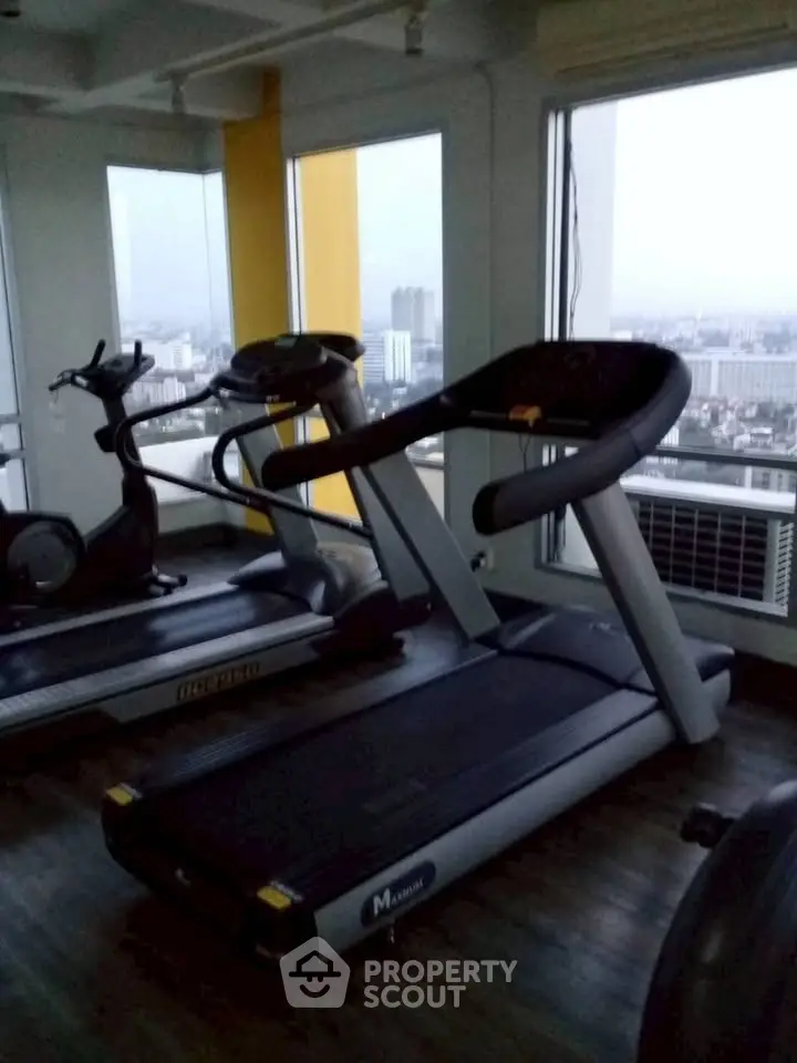 Modern gym with city view featuring treadmills and exercise bikes.