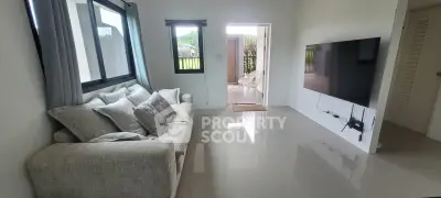 Modern living room with sleek design and large TV, featuring cozy sofa and bright natural light.