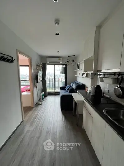 Modern apartment with open kitchen and cozy living area, featuring a balcony with city view.