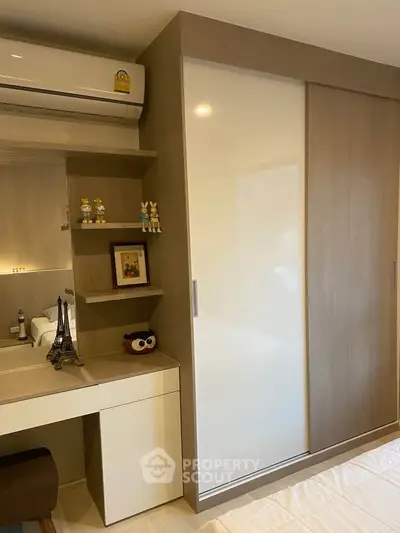 Modern bedroom with sleek wardrobe and stylish decor, featuring a cozy workspace and air conditioning.