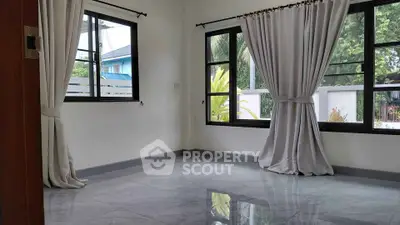 Spacious empty room with large windows and elegant curtains, perfect for customization.
