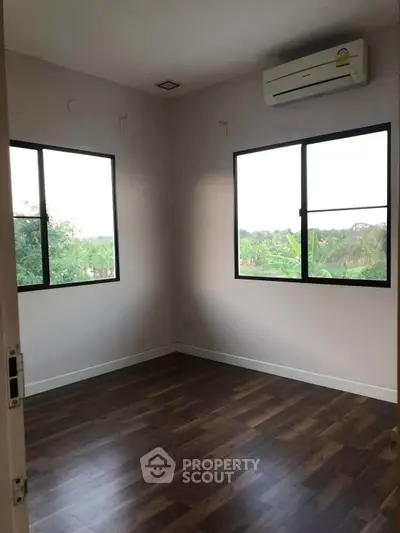 Spacious empty room with large windows and wooden flooring, perfect for customization.