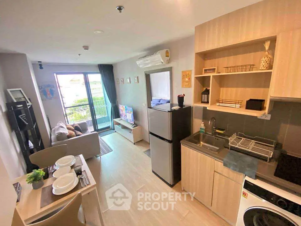 Modern open-layout living room with kitchen, featuring stylish decor and balcony access.