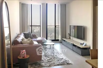 Modern living room with large windows and stylish decor in a high-rise apartment.
