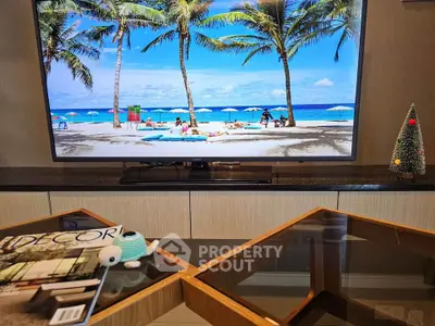 Stylish living room with modern decor and large flat-screen TV displaying a beach scene.