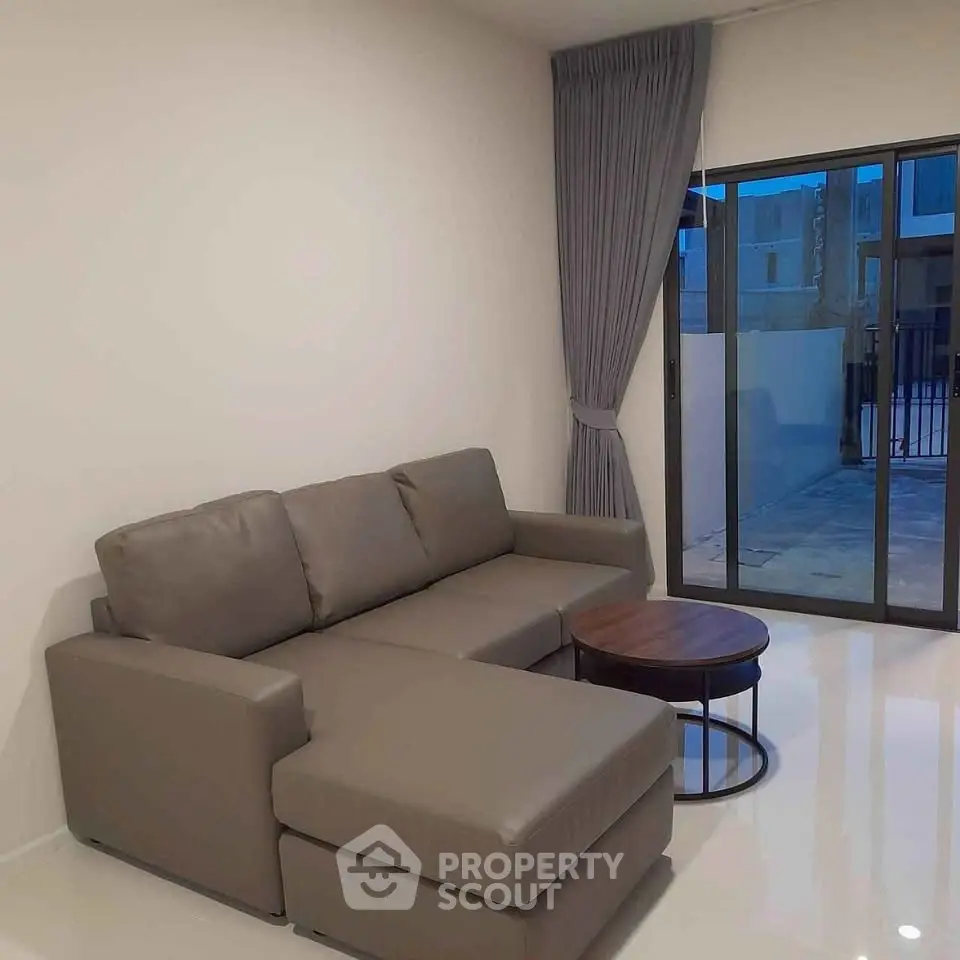 Modern living room with sleek gray sofa and large window offering natural light.