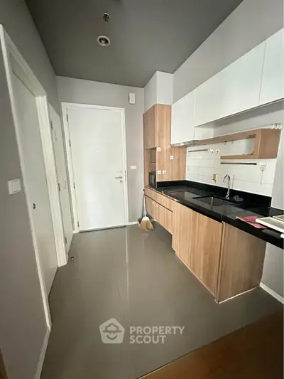 Modern kitchen with sleek cabinetry and black countertops in a compact layout.
