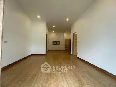 Spacious empty room with wooden flooring and recessed lighting, ideal for customization.