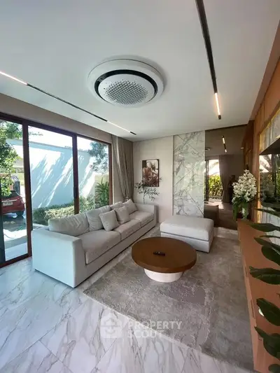 Luxurious living room with modern decor, large windows, and elegant marble flooring.