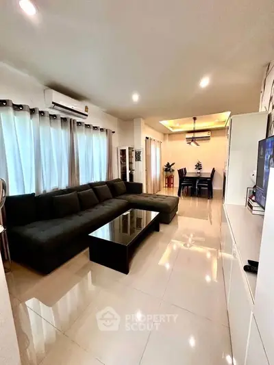 Spacious living room with modern decor and dining area, featuring sleek furniture and ambient lighting.