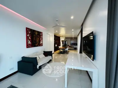 Modern living room with sleek decor and open layout, featuring a large TV and stylish furniture.