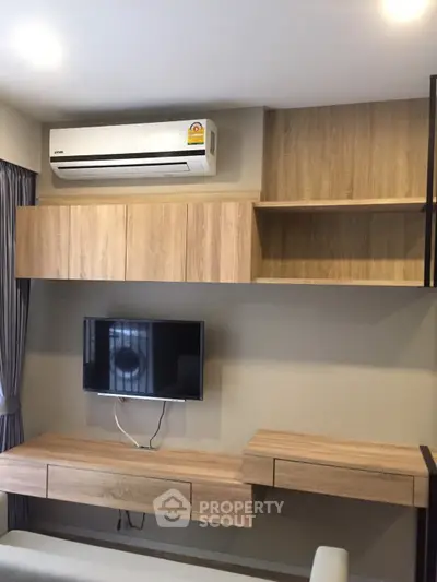 Modern living room with sleek wooden cabinetry and mounted TV, featuring an efficient air conditioning unit.