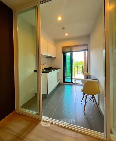 Modern kitchen with open layout and balcony view, featuring sleek cabinetry and stylish dining area.