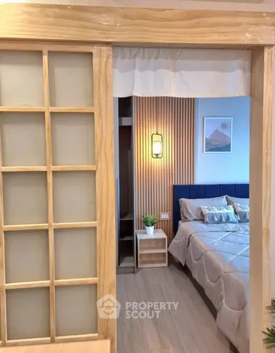 Cozy bedroom with modern decor and sliding wooden door, perfect for relaxation.