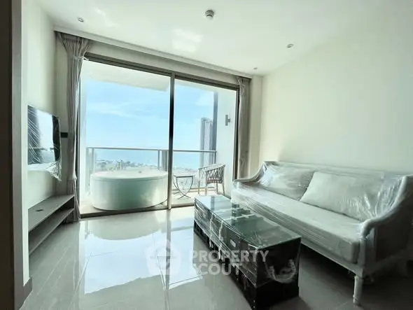 Bright living room with balcony and stunning city view, featuring modern furniture and large windows.