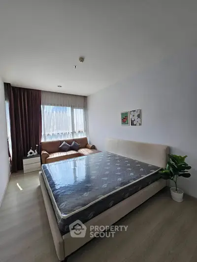 Spacious bedroom with large window, modern decor, and cozy seating area.